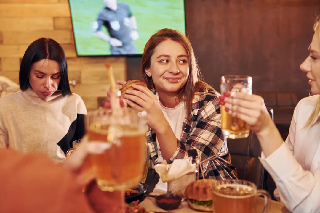 Friends enjoying burgers, fries, and beer in the bar