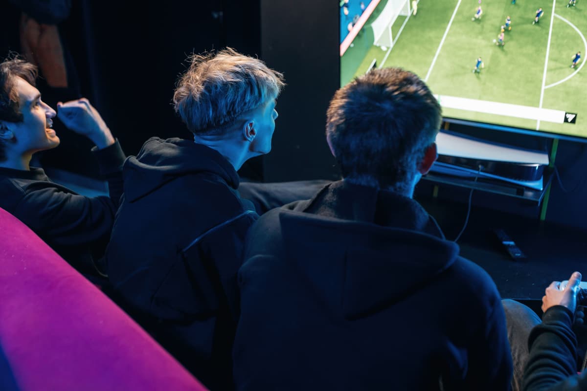 Friends playing a console sports game together in the lounge